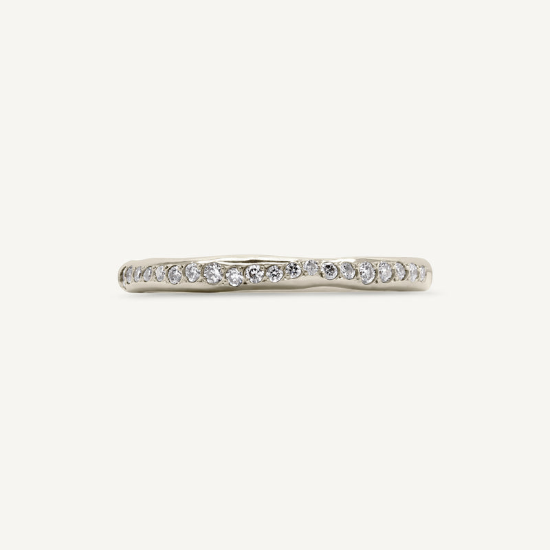A modern and playful eternity ring set with diamonds half way around the band. 100% recycled solid 14ct white gold and ethically sourced gemstones. Handmade by South London jeweller Robyn in her studio.
