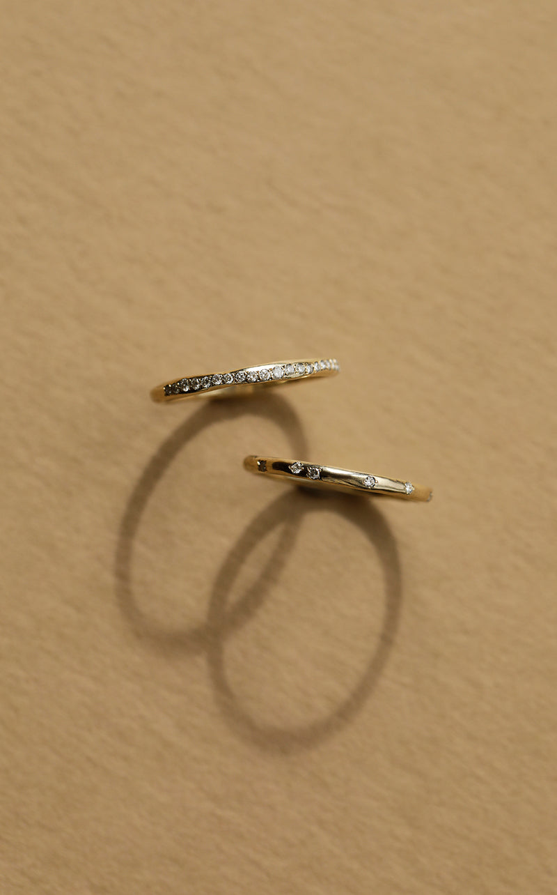 A delicate, slim wedding band made from 100% recycled solid 14ct yellow gold with a lightly textured design set with six scattered diamonds. An unsual alternative wedding ring handmade in South London using ethically sourced gemstones.