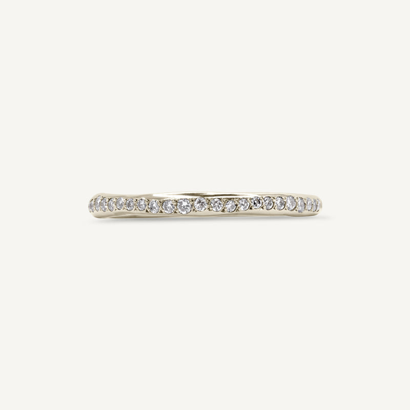 A modern and playful slim eternity ring set with a delicate line of diamonds half way around the band. 100% recycled solid 14ct white gold and ethically sourced gemstones. Handmade by South London jewellery designer Robyn in her studio.