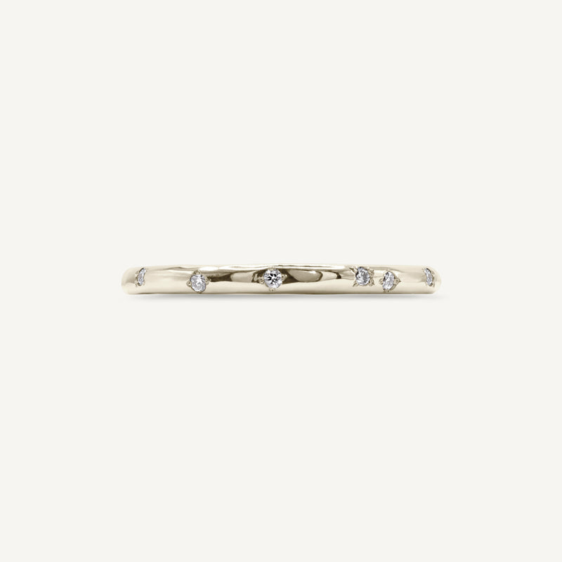 A delicate, slim wedding band made from 100% recycled solid 14ct white gold with a lightly textured design set with six scattered diamonds. An unusual alternative wedding ring handmade in South London using ethically sourced gemstones.