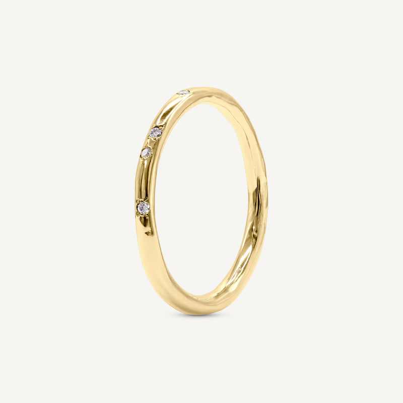 A delicate, slim wedding band made from 100% recycled solid 14ct yellow gold with a lightly textured design set with six scattered diamonds. An unusual alternative wedding ring handmade in South London using ethically sourced gemstones.