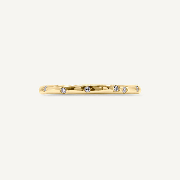 A delicate, slim wedding band made from 100% recycled solid 14ct yellow gold with a lightly textured design set with six scattered diamonds. An unsual alternative wedding ring handmade in South London using ethically sourced gemstones.