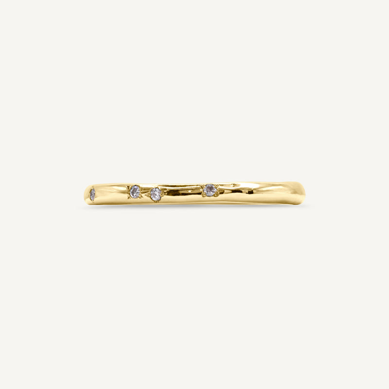 A delicate, slim wedding band made from 100% recycled solid 14ct yellow gold with a lightly textured design set with six scattered diamonds. An unusual alternative wedding ring handmade in South London using ethically sourced gemstones.