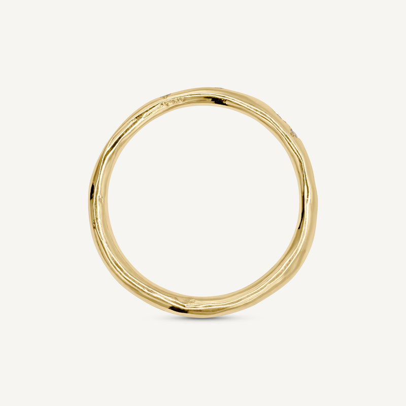 A delicate, slim wedding band made from 100% recycled solid 14ct yellow gold with a lightly textured design set with six scattered diamonds. An unusual alternative wedding ring handmade in South London using ethically sourced gemstones.