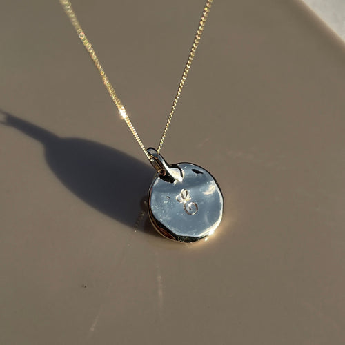 Engraved E disc ripple pendant inspired by ancient artefacts and ancient antique jewellery | Womens and Mens custom pendants available in 9ct, 14ct, 18ct gold and platinum | Crafted from 100% recycled metals in south London with the philosophy that roughness and refinement can coexist